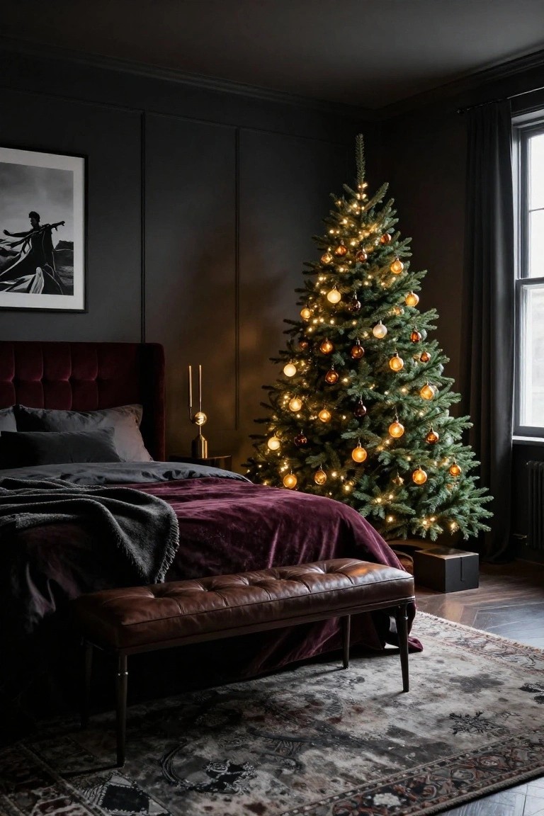 A lit Christmas tree with gold and amber ornaments stands next to a burgundy velvet bed in a dark gray paneled bedroom with gray sheets, a throw blanket, gold candlesticks, and a leather bench on a patterned rug.