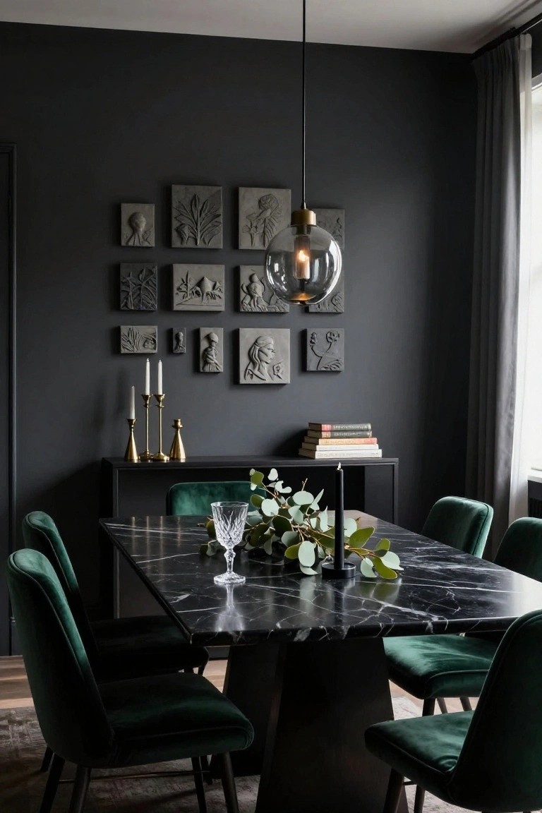Dark gray dining room with black marble table, green velvet chairs, eucalyptus centerpiece in glass vase, gold candelabras on black sideboard, and gray plaster relief panels on walls.