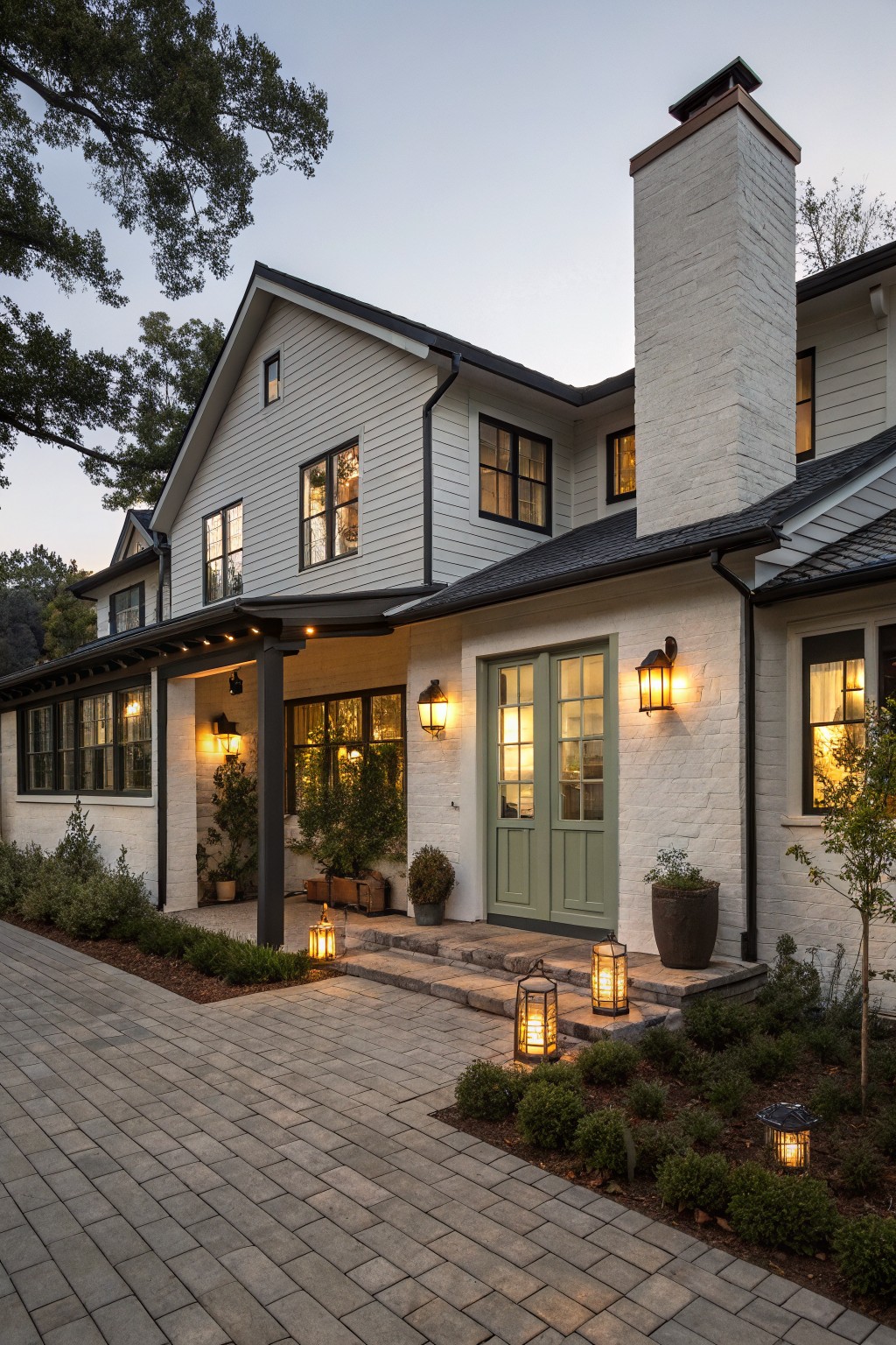 White house with green door, brick chimney, and glowing lanterns at dusk.