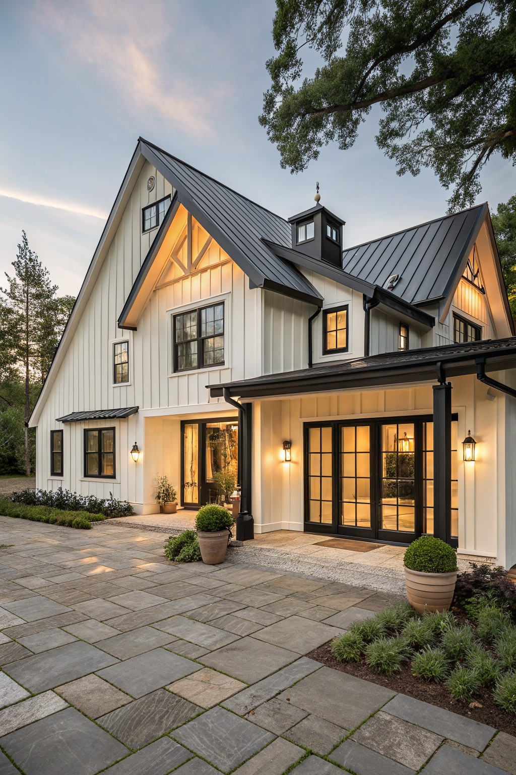 A modern farmhouse house with white board-and-batten siding, black standing-seam metal roof, black-trimmed windows and doors, covered entry porch, and paver driveway with landscaping.