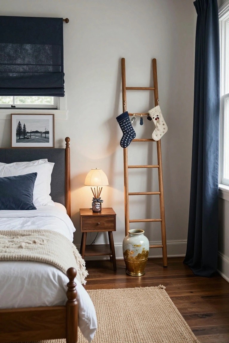 Bedroom corner featuring a tall wooden ladder with two Christmas stockings hanging from it, next to a bed with navy pillows and white duvet, wooden nightstand, and navy curtains.
