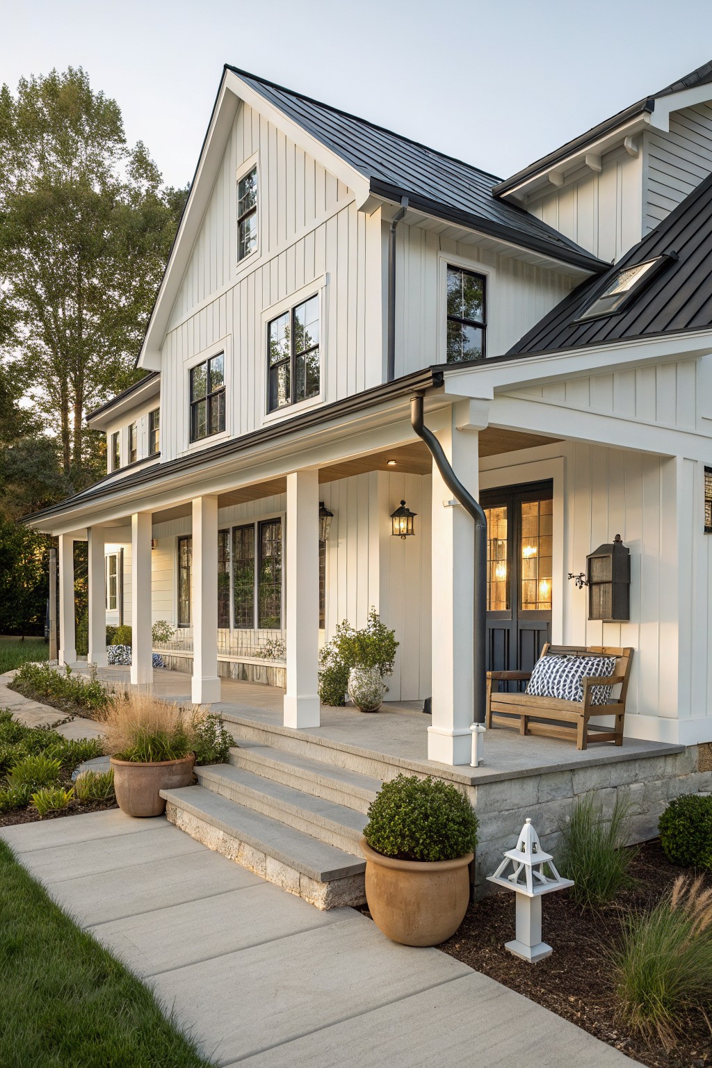 Modern white farmhouse with black metal roof, porch, and stone steps.