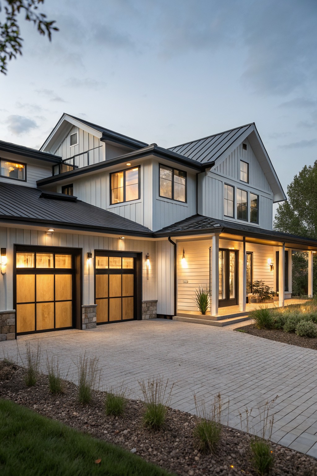 Two-car garage on a modern farmhouse exterior with black-framed doors featuring horizontal wood panels over glass, flanked by stone accents, plus a covered porch and paver driveway at evening.