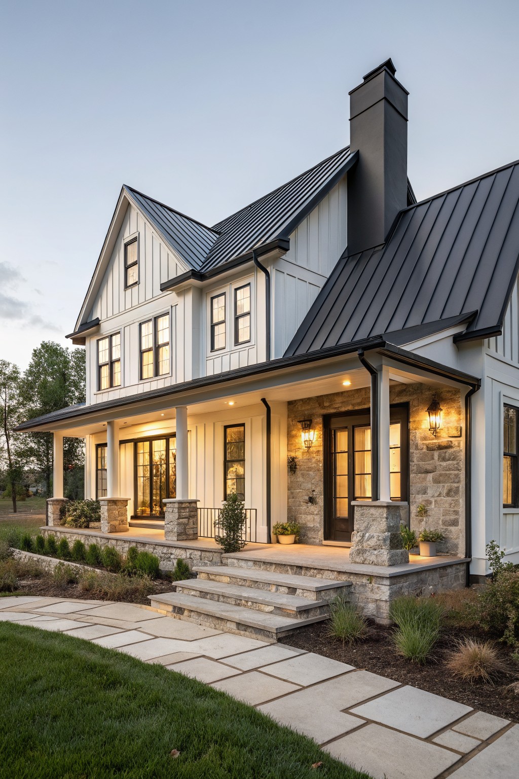 Modern farmhouse with dark metal roof and stone porch at dusk.