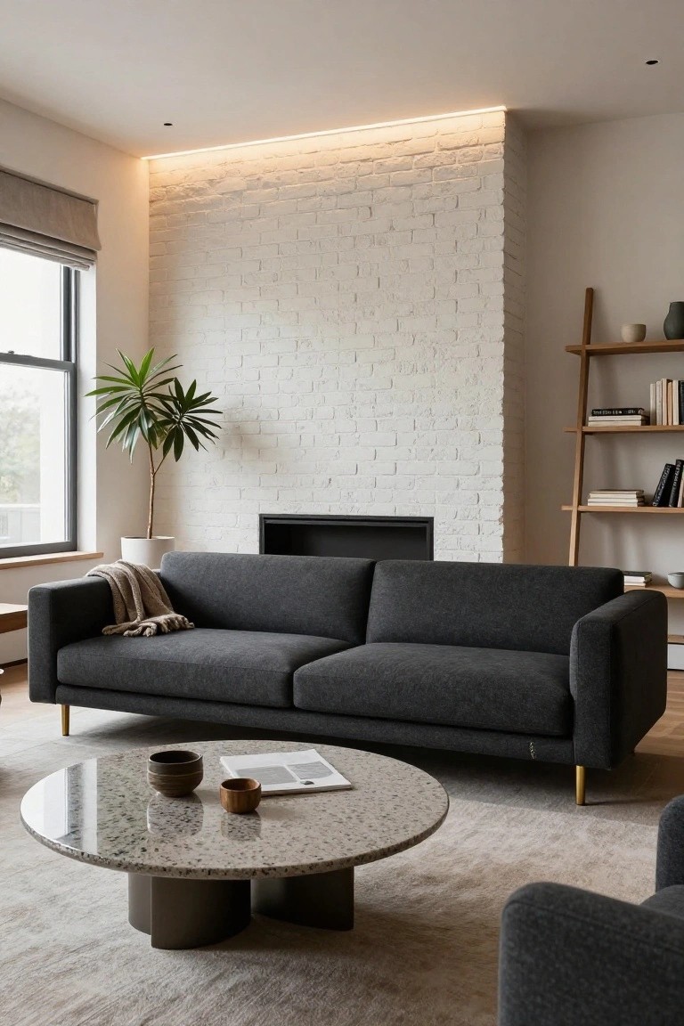 Modern living room with gray sofa, round stone coffee table, and white brick wall.