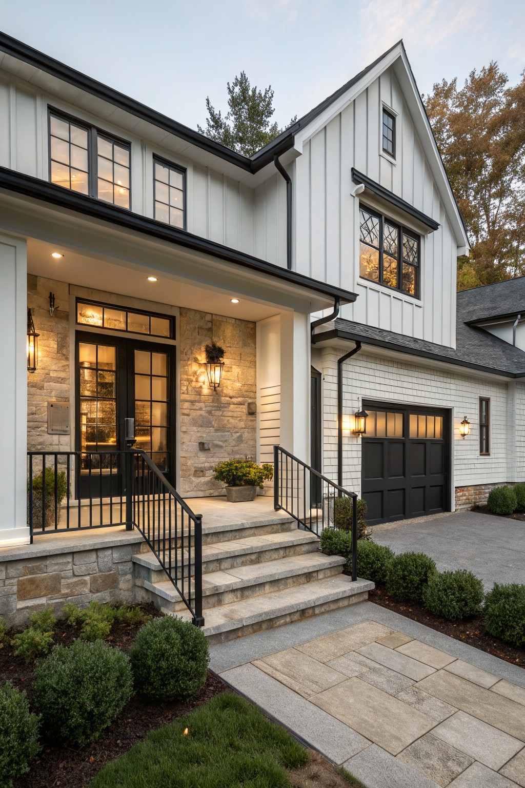 Two-story modern farmhouse exterior with white shiplap siding, black-framed windows and double doors, stone entry surround, black metal porch railing and garage door, flanked by landscaping at dusk.