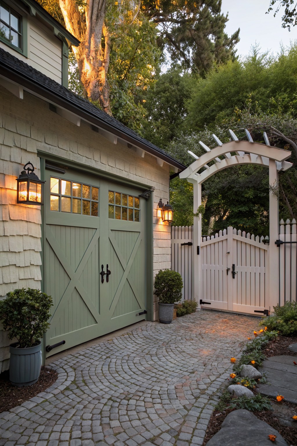 Green garage doors on house beside white arched gate and cobblestone path.