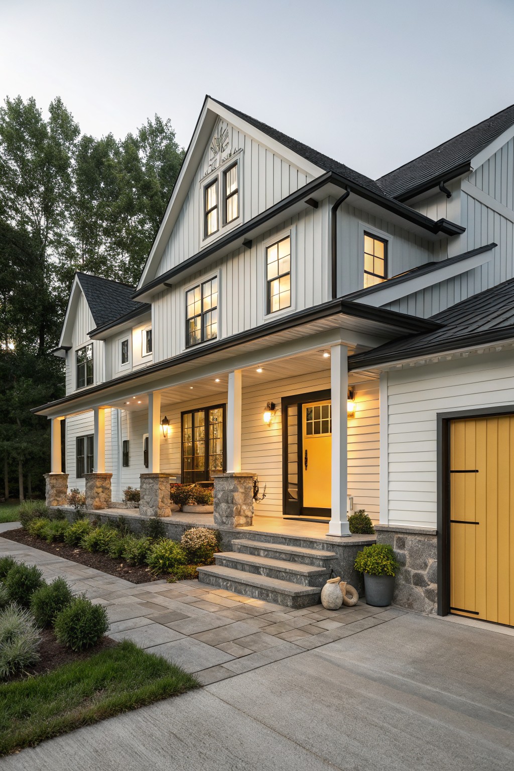 Two-story modern farmhouse exterior with white board-and-batten siding, black metal roof and trim, yellow front door, wraparound porch with stone pillars, and landscaping at dusk.