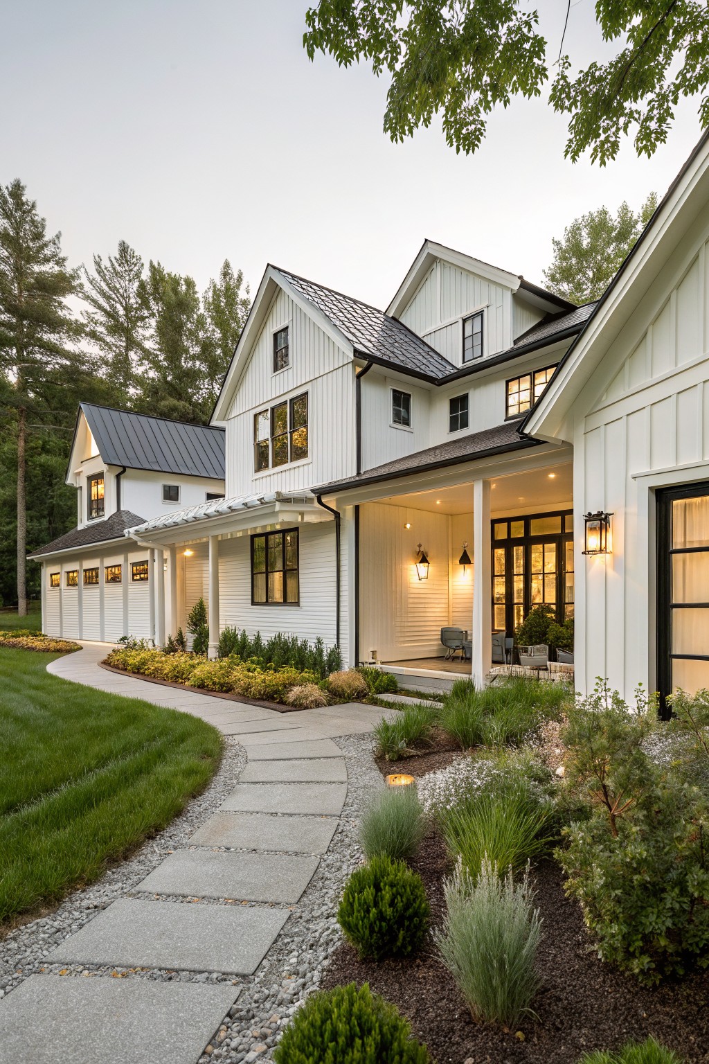 White board and batten sided modern farmhouse exterior featuring attached multi-bay garage, covered porch with columns, black-framed windows and doors, metal roofs, and a curved stone pathway with gravel beds and shrubs.
