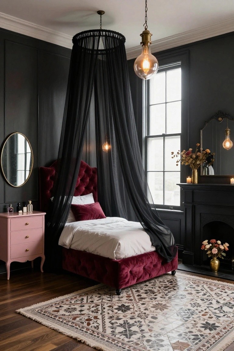 Corner bedroom with charcoal paneled walls, burgundy velvet tufted bed under black sheer canopy from ceiling fixture, pink dresser, round mirror, candles on mantel, and window with sheer curtains.