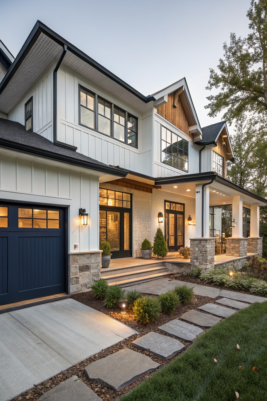 Two-story modern farmhouse exterior with navy blue paneled garage door, white board-and-batten siding, black window frames, wooden gable accents, covered porch with glass doors, stone pillars, and flagstone path to entry.
