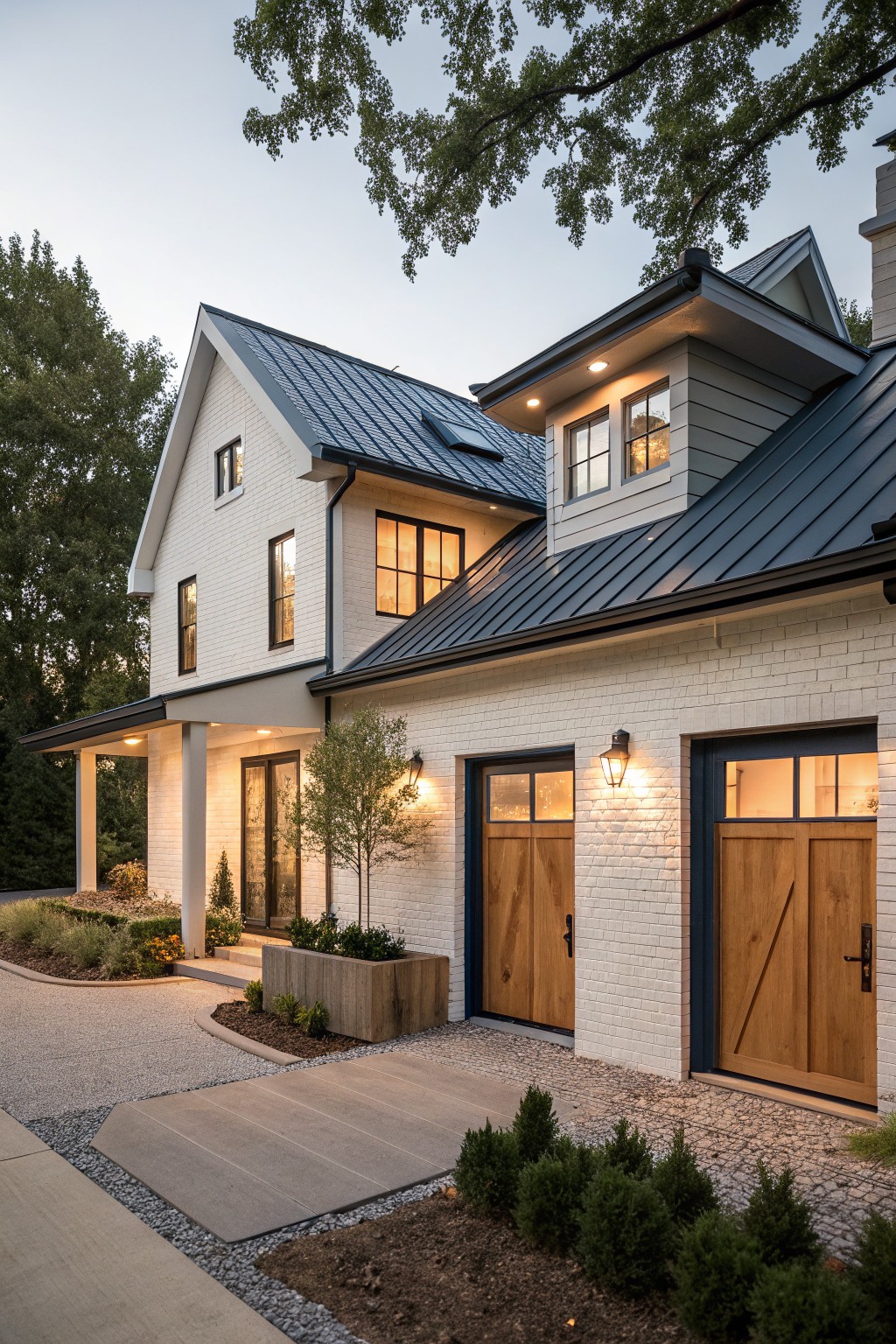 Two-story modern farmhouse exterior with white brick walls, navy blue standing-seam metal roof, wooden double garage doors with blue frames, covered porch, and landscaped driveway at dusk.