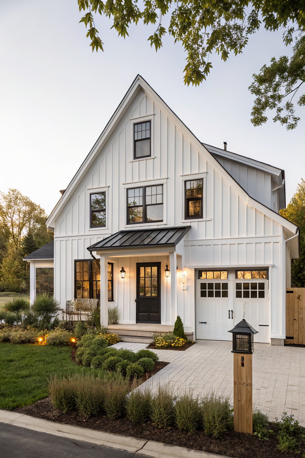 White board-and-batten sided modern farmhouse with asymmetric gable roof, black metal awning over the entry porch and garage, black front door with lanterns, and landscaped front yard with pavers and shrubs.