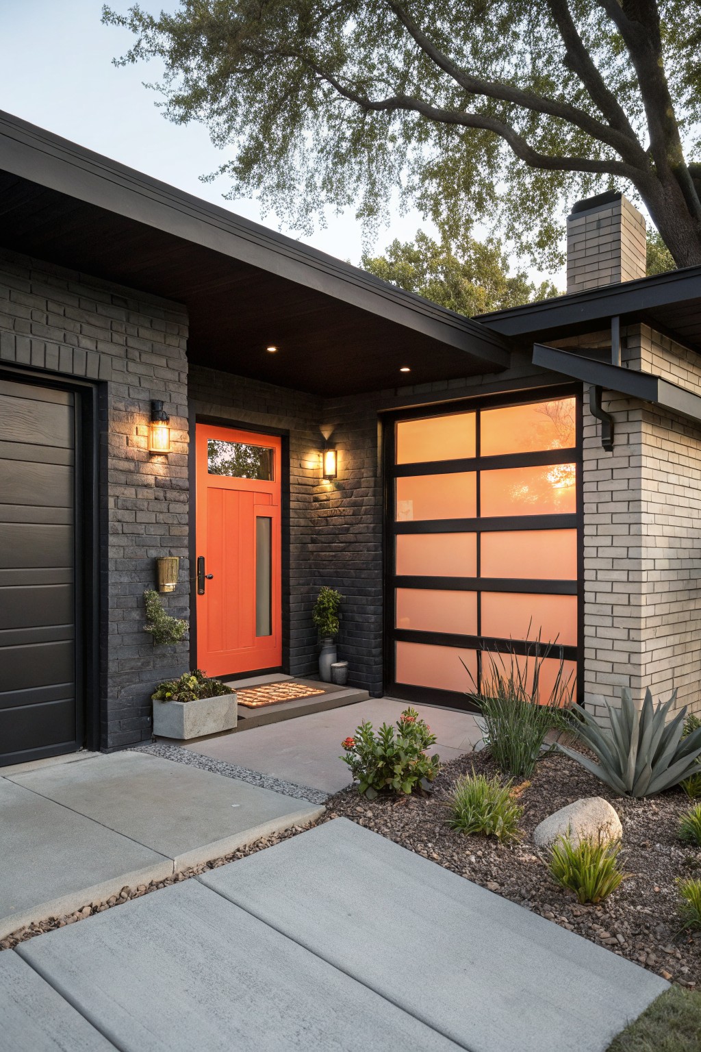 Ranch-style house exterior featuring black painted brick walls, an orange front door with sidelight, black garage door with frosted glass panels, wall-mounted lanterns, potted plants, and gravel landscaping with agave and grasses.