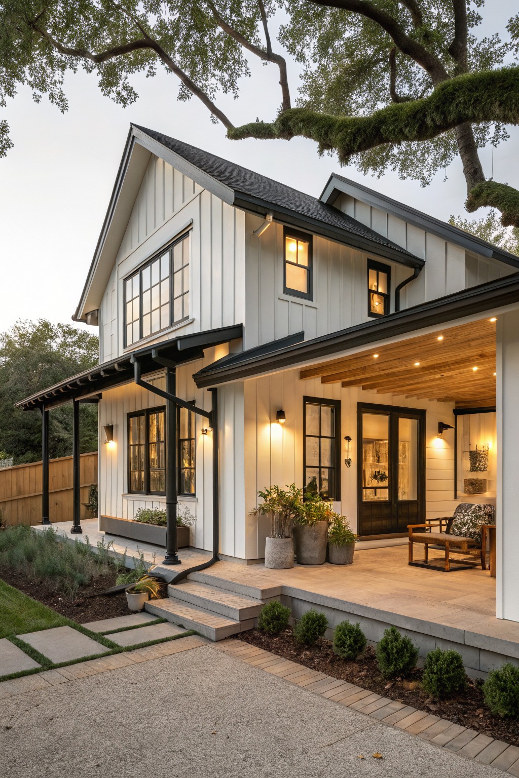 White board-and-batten sided one-story house with black-trimmed windows and roof, covered porch with wood beam ceiling and black posts, potted plants, steps, and gravel path in front.