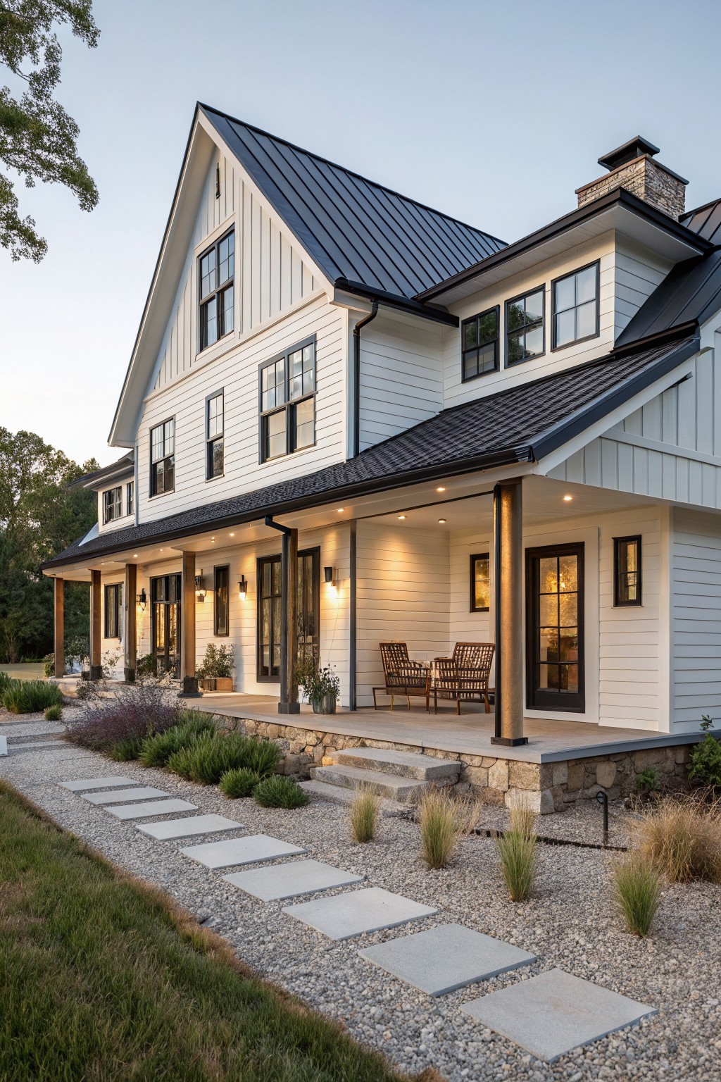 A two-story white farmhouse exterior with black metal roofing, board and batten siding, a stone porch base, and multiple windows.