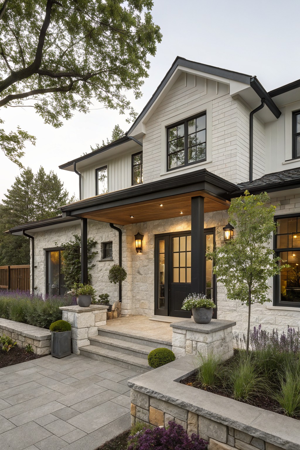 Front view of a two-story house with white siding, stone veneer on the lower facade and porch supports, black window frames and trim, and a covered entry with wood ceiling.