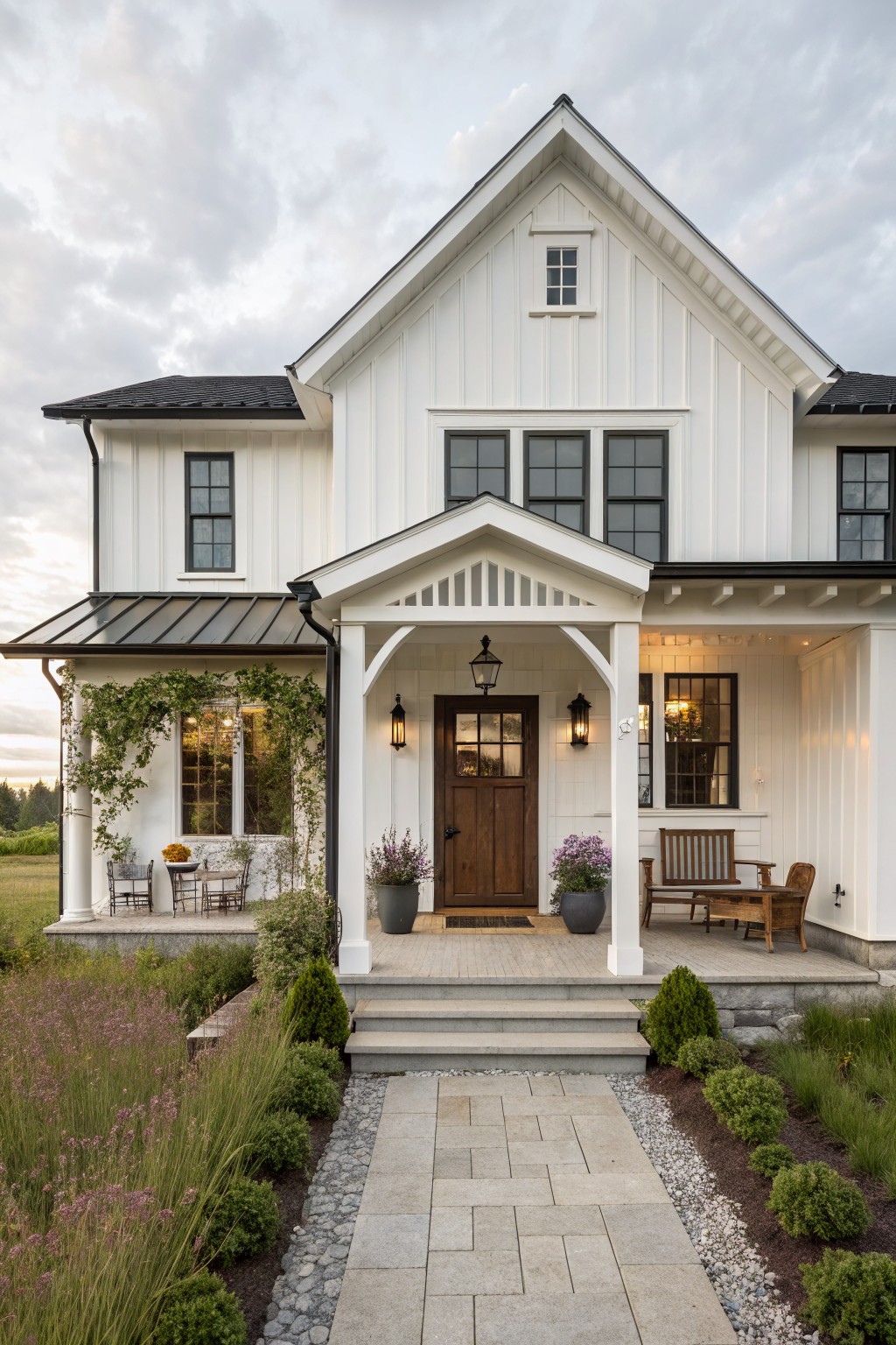 A white two-story farmhouse with a central gabled front porch, dark wood door, and stone pathway leading to the steps.