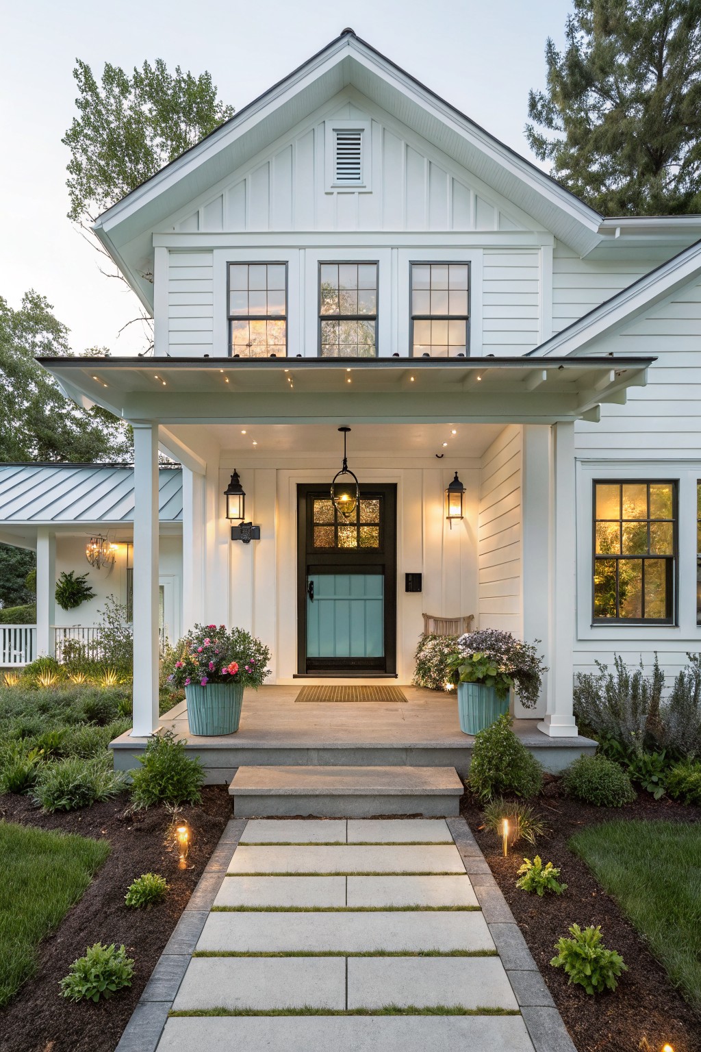 Front view of a small white farmhouse with a dark front door under a covered porch, two potted plants on the steps, and pathway leading to the entrance.