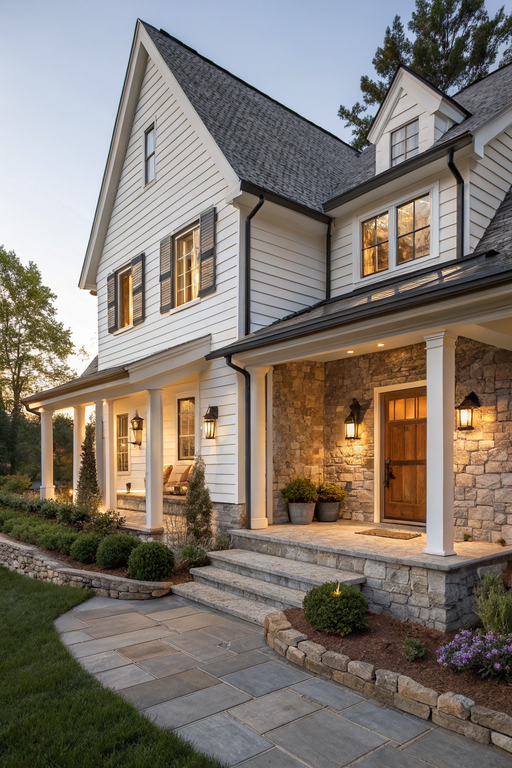 White two-story farmhouse with dark gray roof, stone veneer on the porch walls and entry, white columns, and a stone walkway in front.