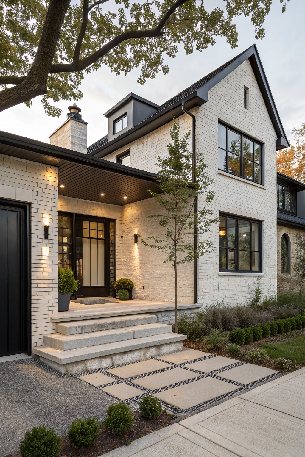 Front view of a modern farmhouse with white painted brick, black window frames and trim, a covered porch with steps, and a stone paver walkway.