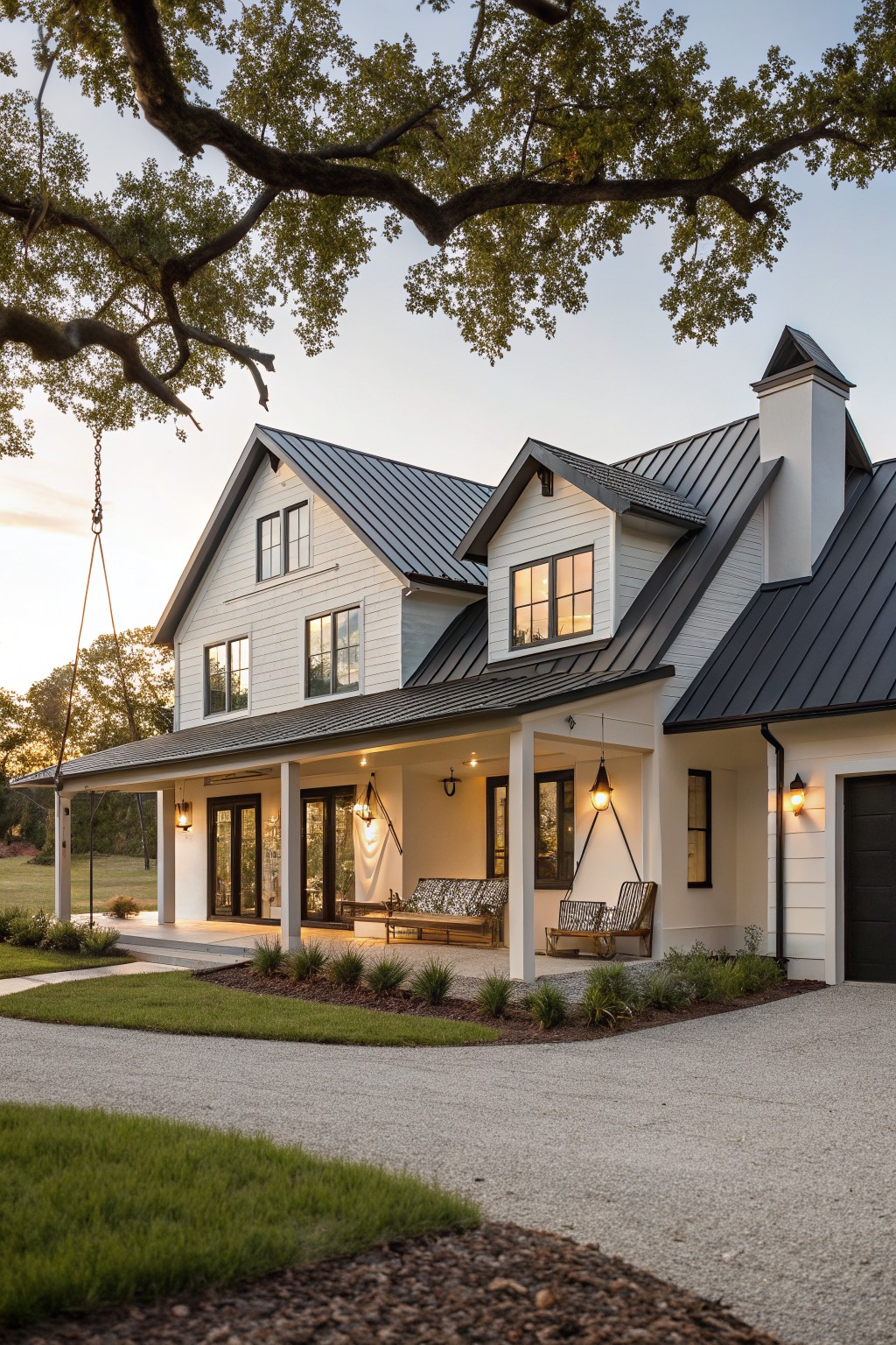 A white modern farmhouse with a dark metal roof, covered porch, and gravel driveway at dusk.