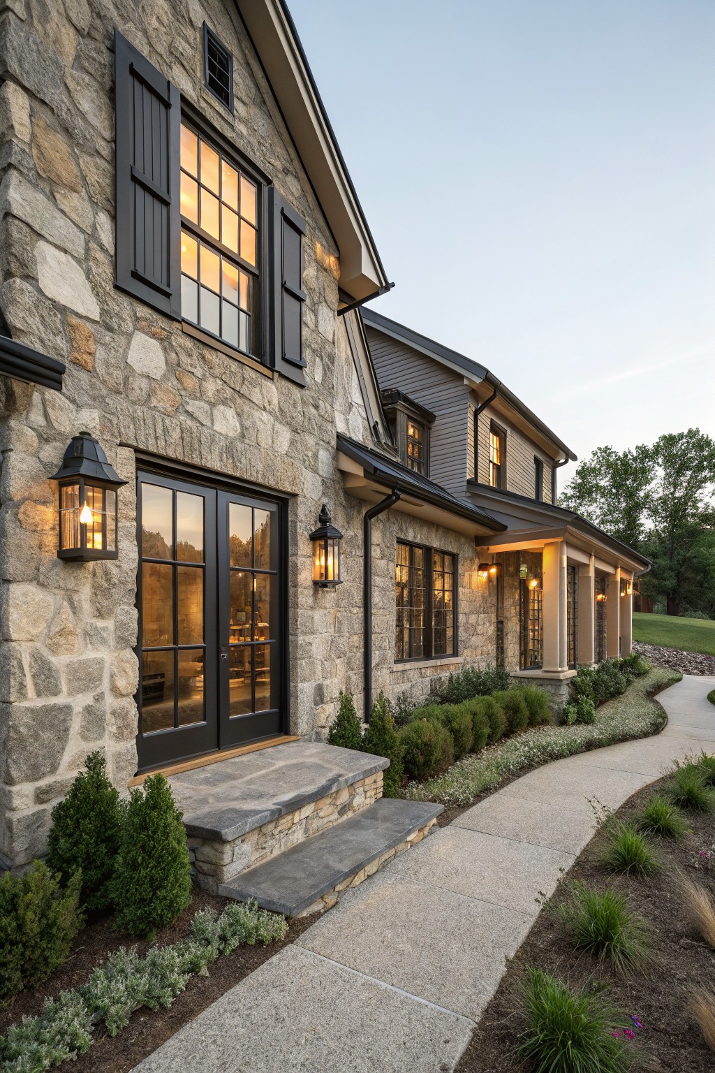 Stone house exterior with black shutters flanking a large window and black double doors at the entry.