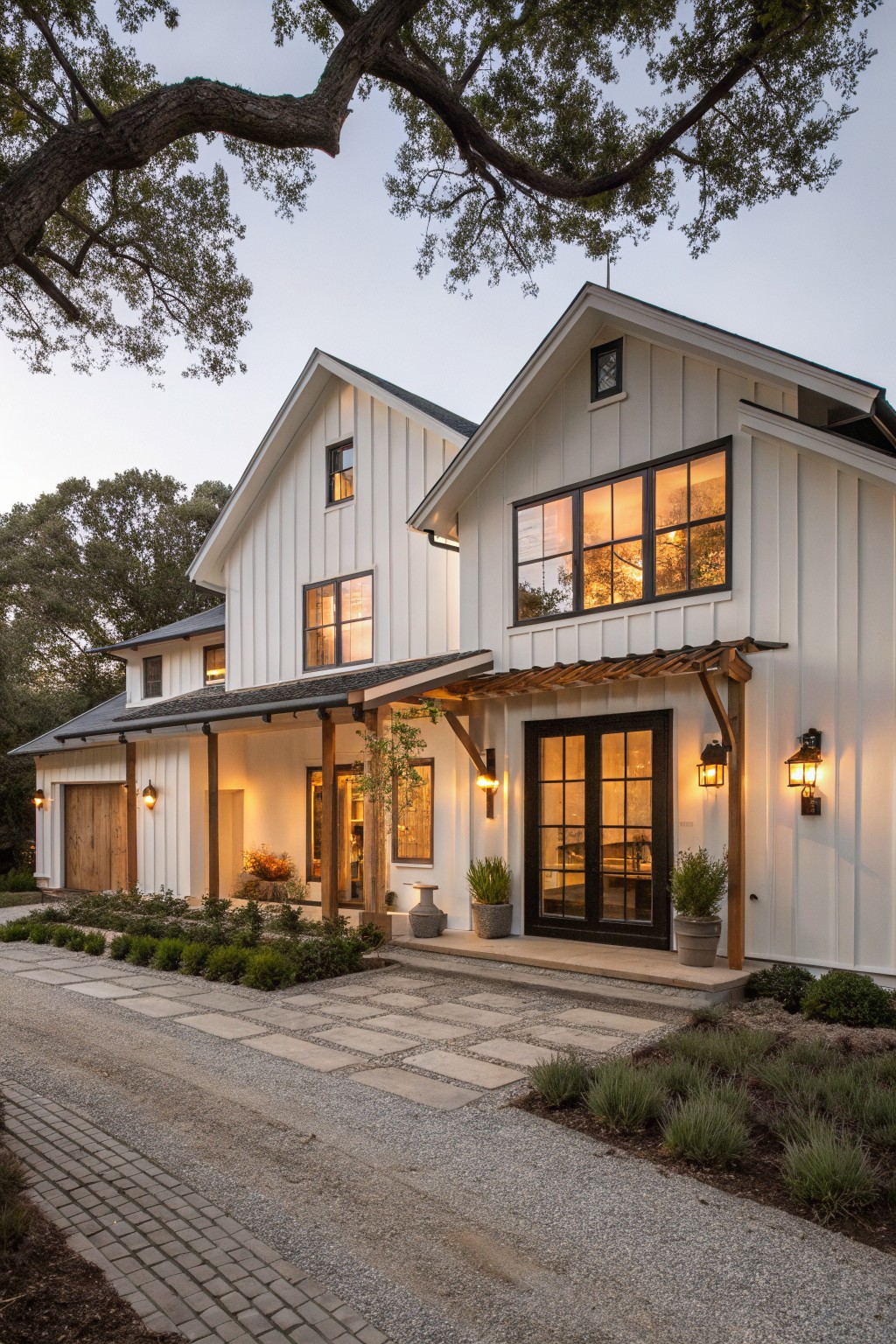 A two-story white farmhouse with vertical siding, black window frames, a wooden entry canopy, and a stone pathway leading to the front.