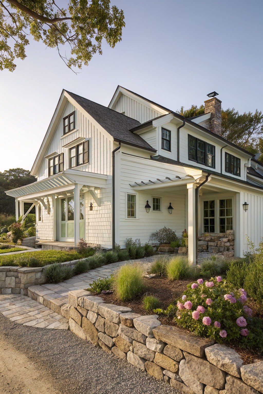 A white two-story farmhouse with dark roofing, multiple gables, a stone chimney, and a covered front porch.