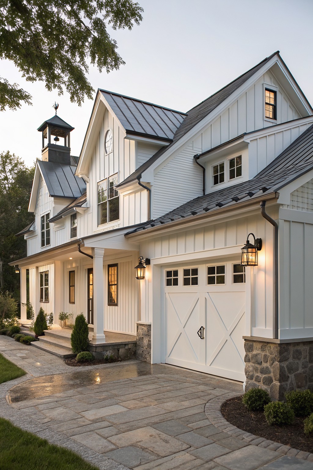 A white two-story farmhouse with an attached garage, white cross-panel doors, and stone base under soft evening light.