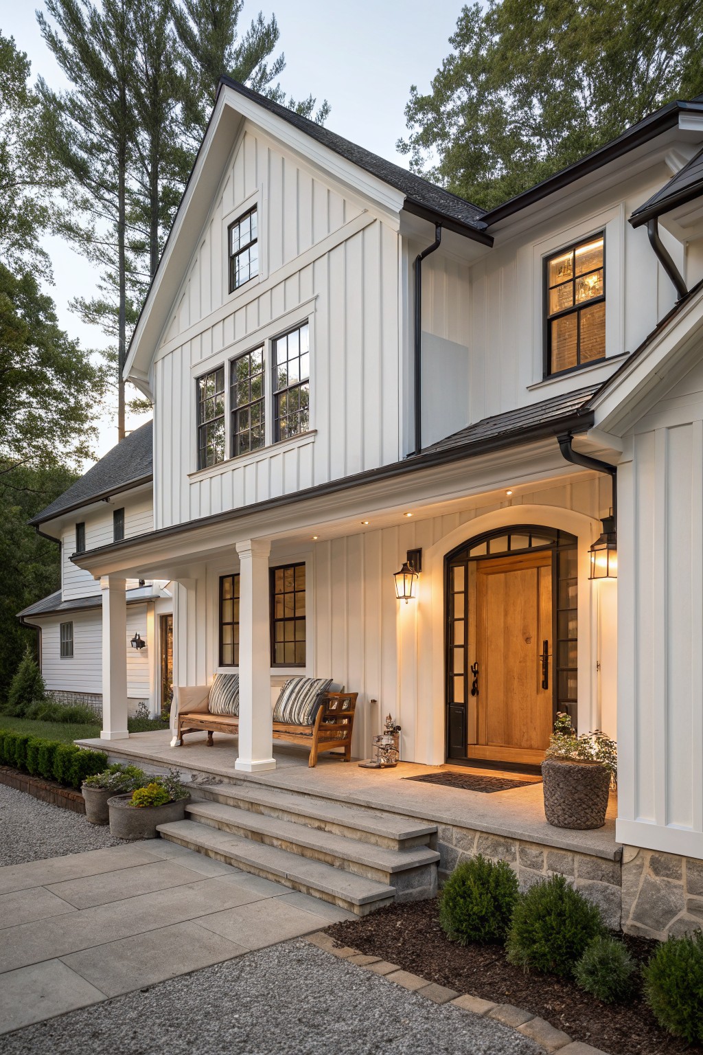 White two-story farmhouse with wooden door, lit porch, and stone steps