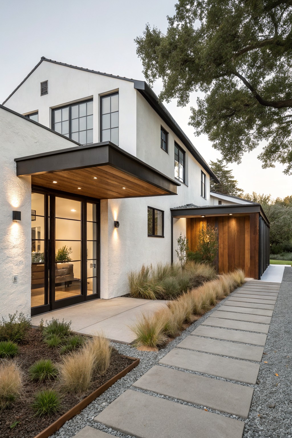 Modern white house with black-framed doors, wooden canopy, and stone pathway.