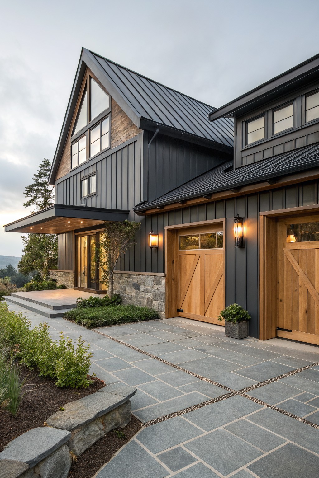A modern coastal farmhouse exterior with a dark metal roof, dark siding, and large wooden garage doors set on a stone and paved driveway.