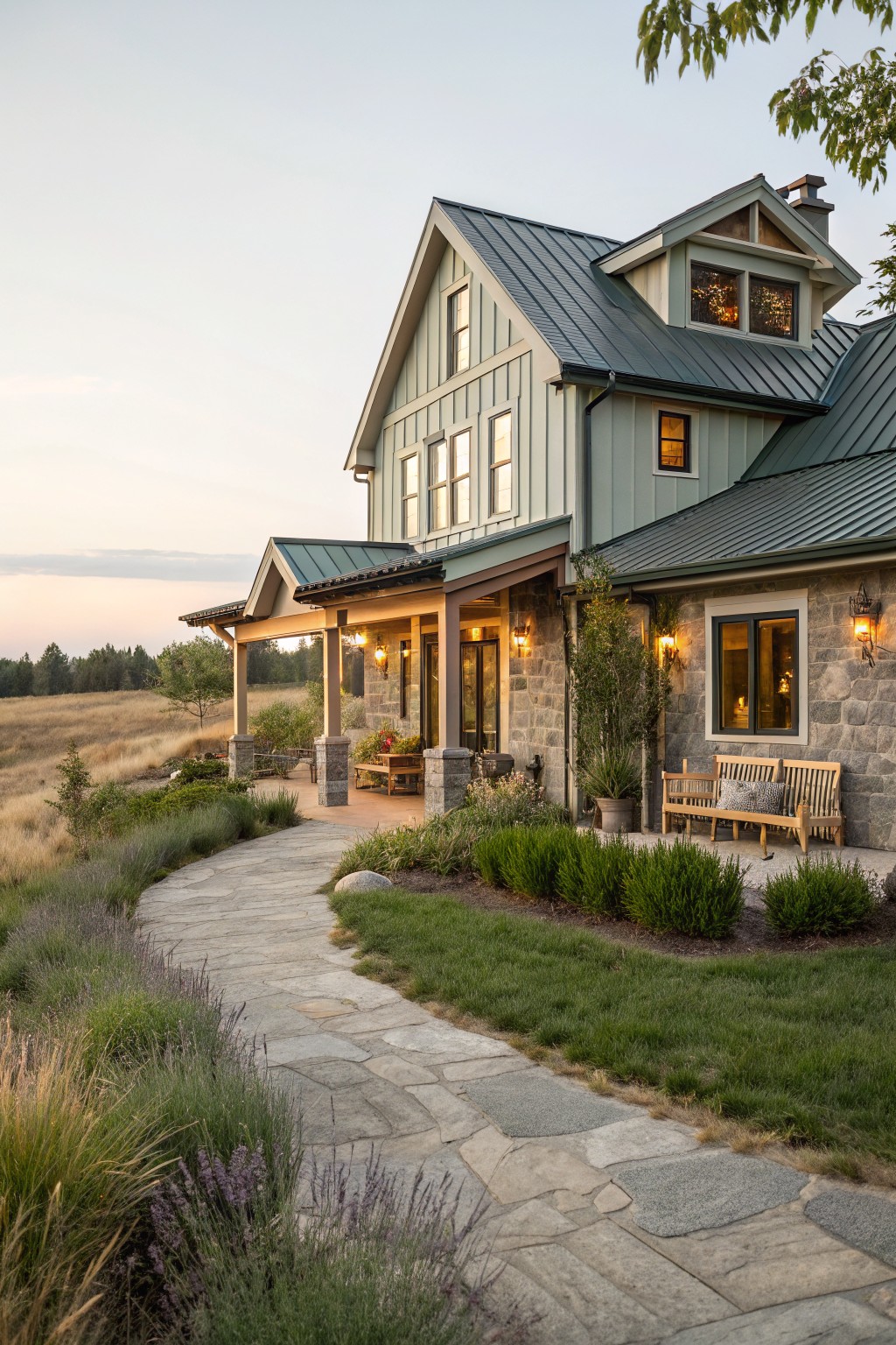 A two-story coastal farmhouse with light green siding, a dark green metal roof, stone accents on the lower walls, and a covered porch with wood posts.