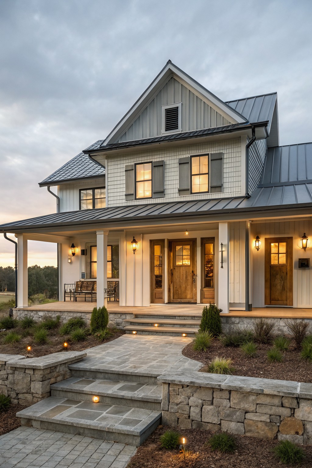 Front view of a two-story white farmhouse with a dark metal roof, multiple wooden entry doors, and a covered porch.