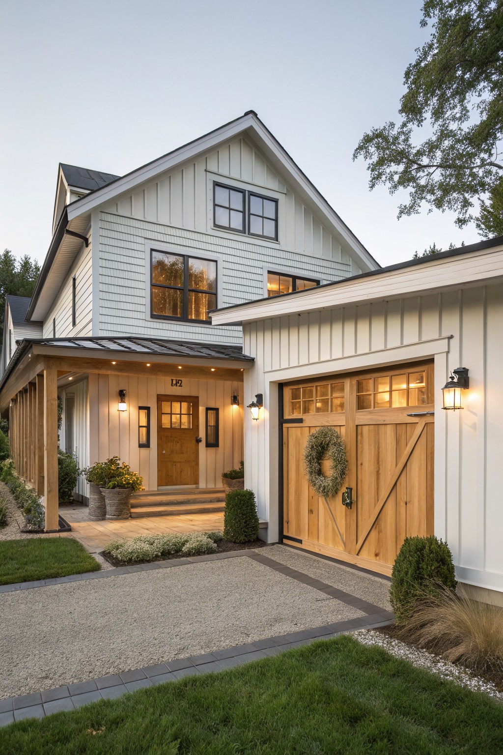 A white farmhouse exterior with natural wood garage doors and a wooden front door, set on a gravel driveway with landscaping.