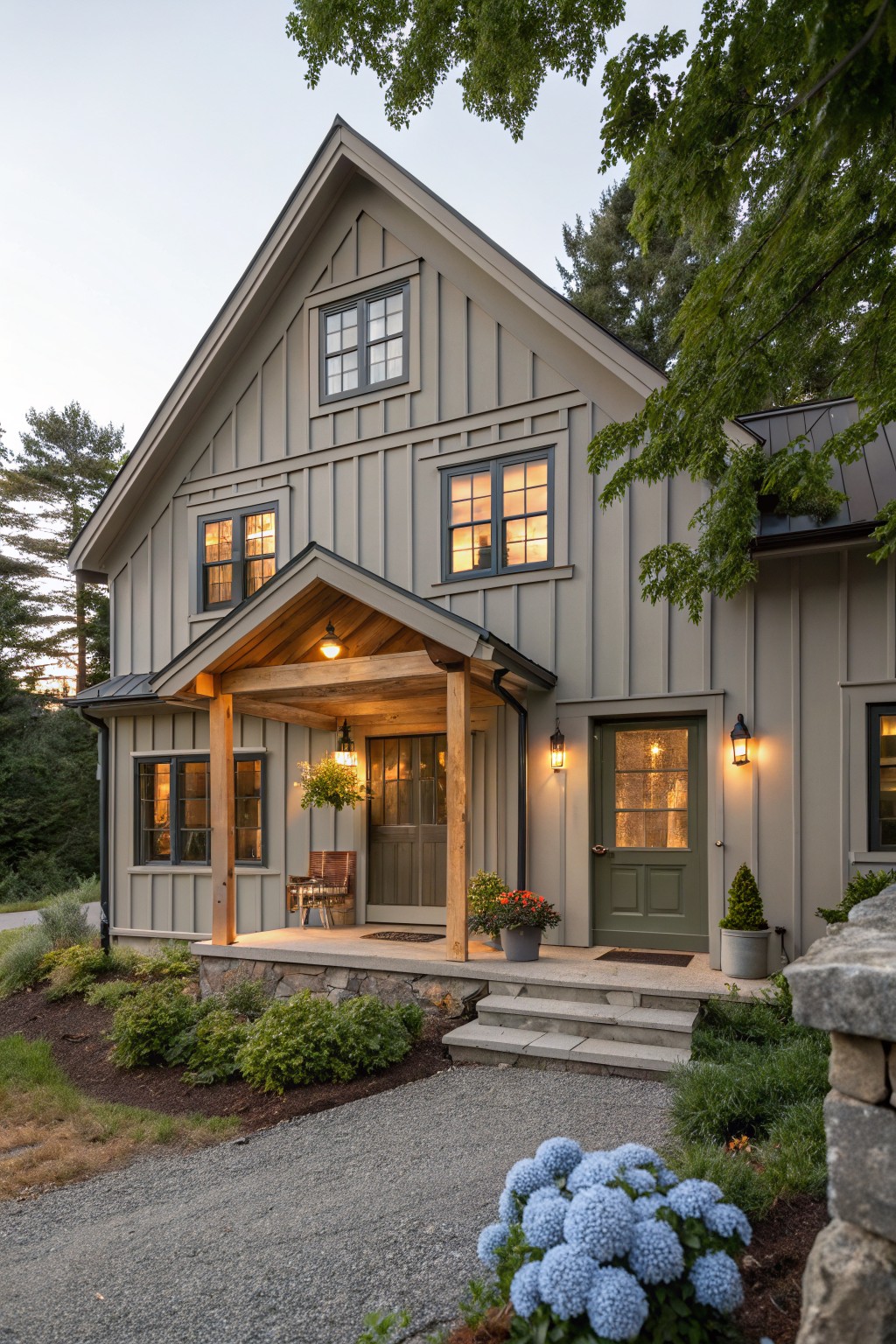 Front view of a compact two-story house with gray siding, a gabled wooden porch entry, and a green front door.