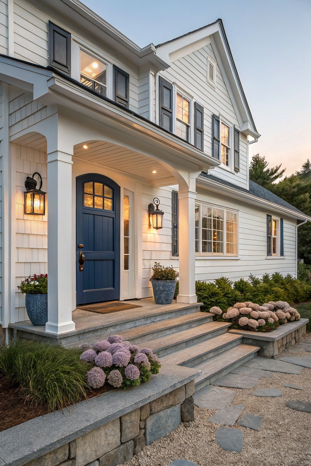 Front view of a white two-story house with a navy blue front door, white columns, stone steps, and a gravel path.
