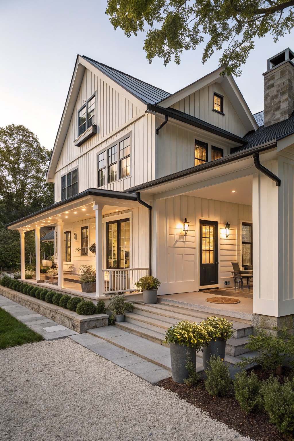 A white two-story house with vertical siding, black trim and roof, a covered front porch, and concrete steps flanked by potted plants.