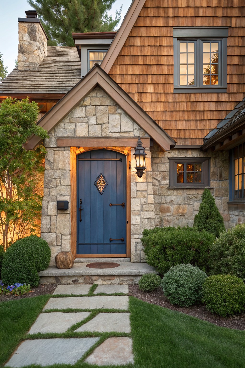 Blue door in stone gable of shingled house with flagstone path and lantern