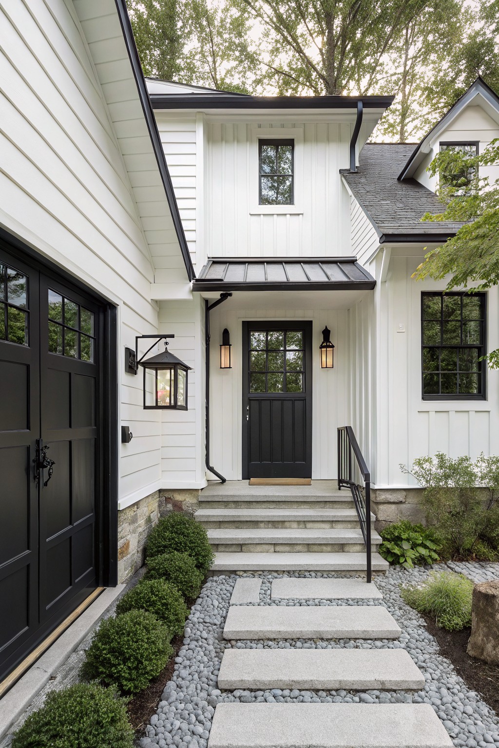 A white house exterior with black trim, a black front door, and stone steps leading up from a gravel path.