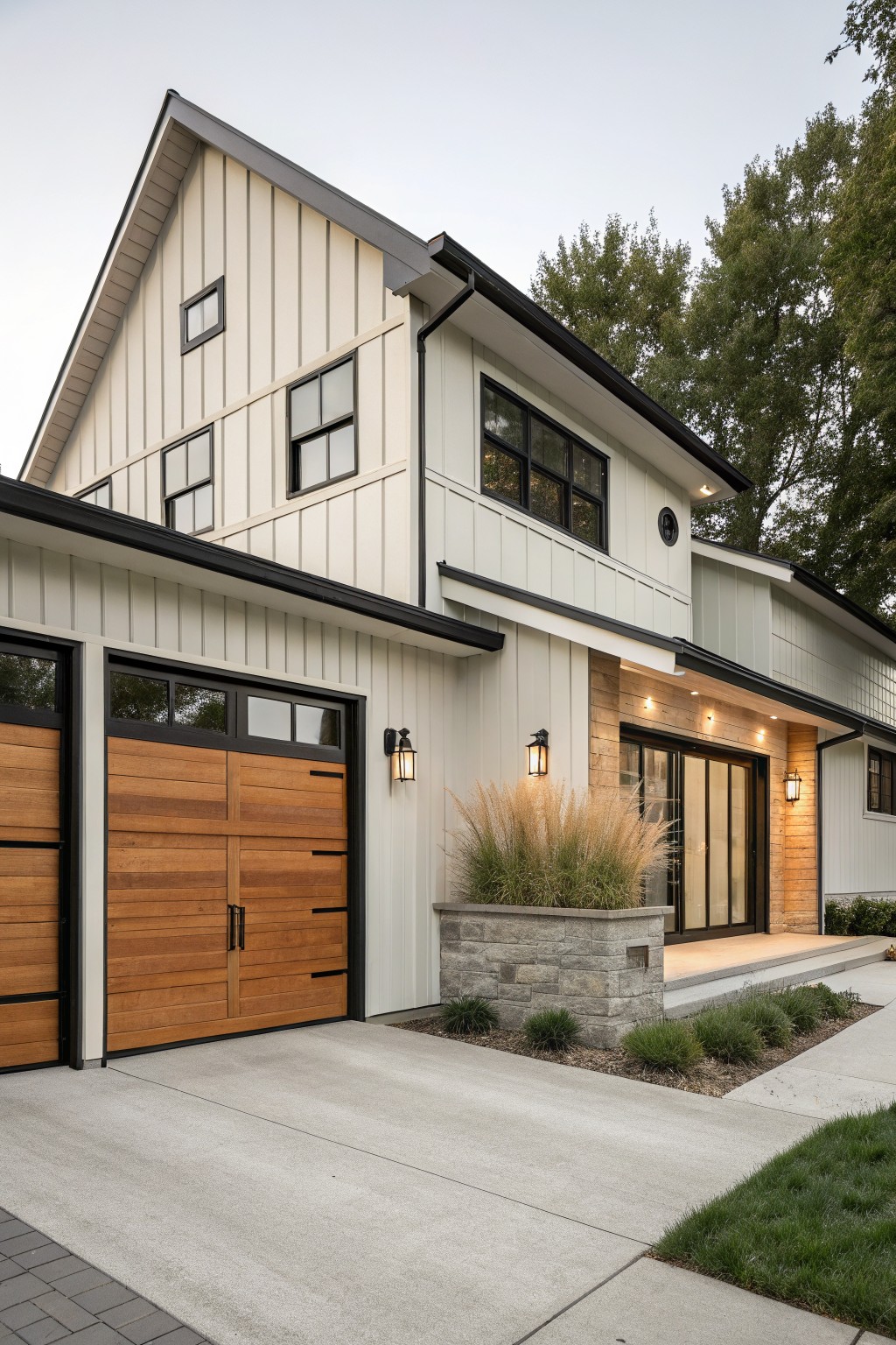 Front view of a two-story house with creamy white vertical siding, black trim, a wooden garage door, and a stone planter beside the entry.