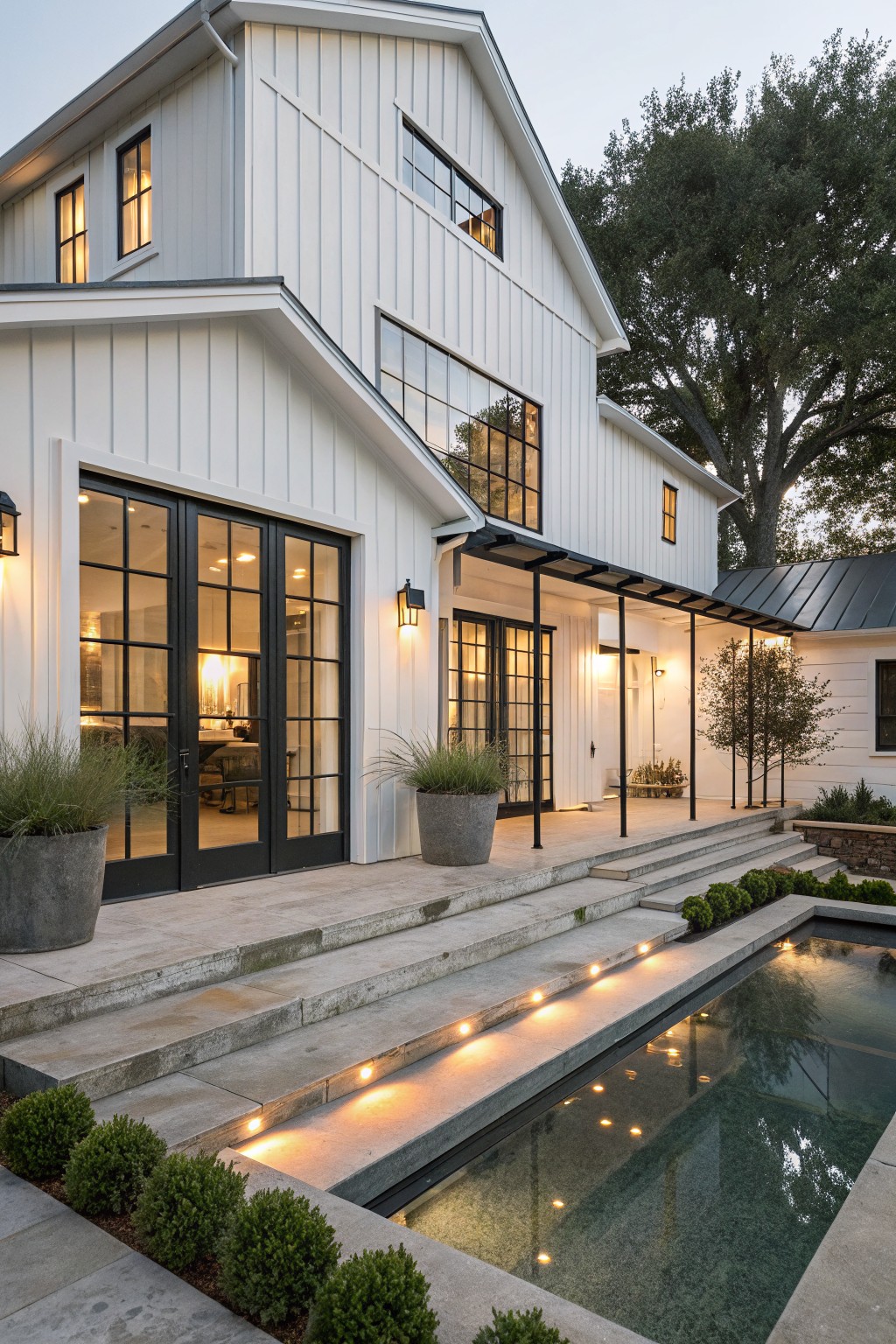 Modern white house with black windows beside illuminated rectangular pool at dusk