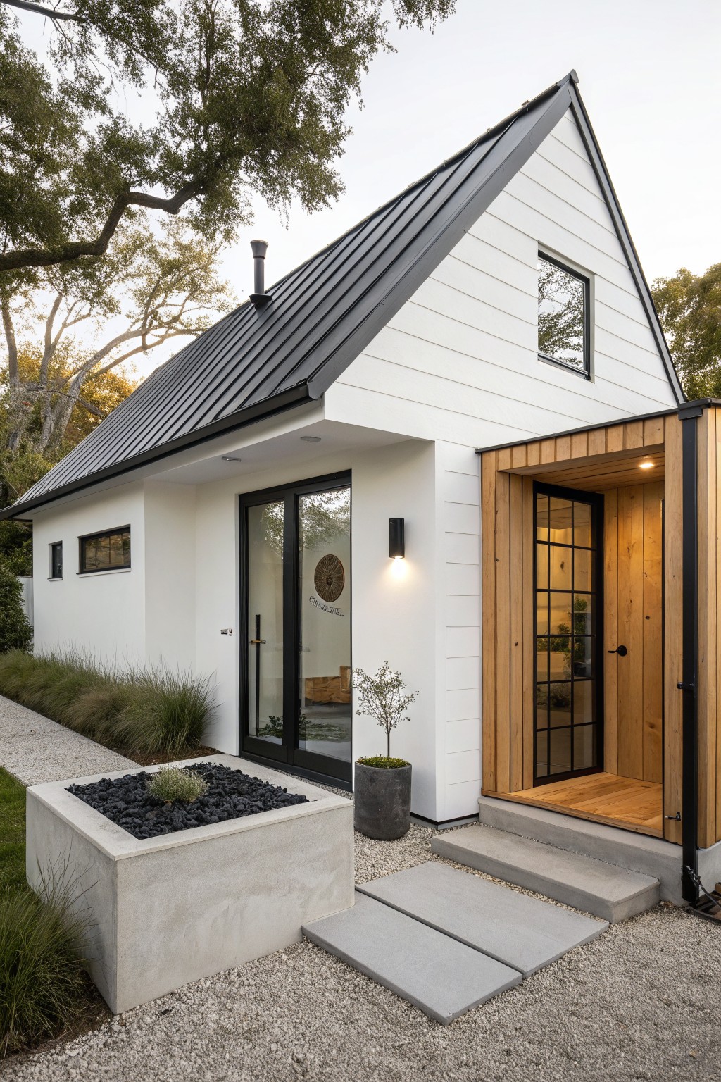 A white farmhouse exterior with a black metal roof, black-framed doors and windows, a wooden entry surround, and concrete steps leading to the front door.
