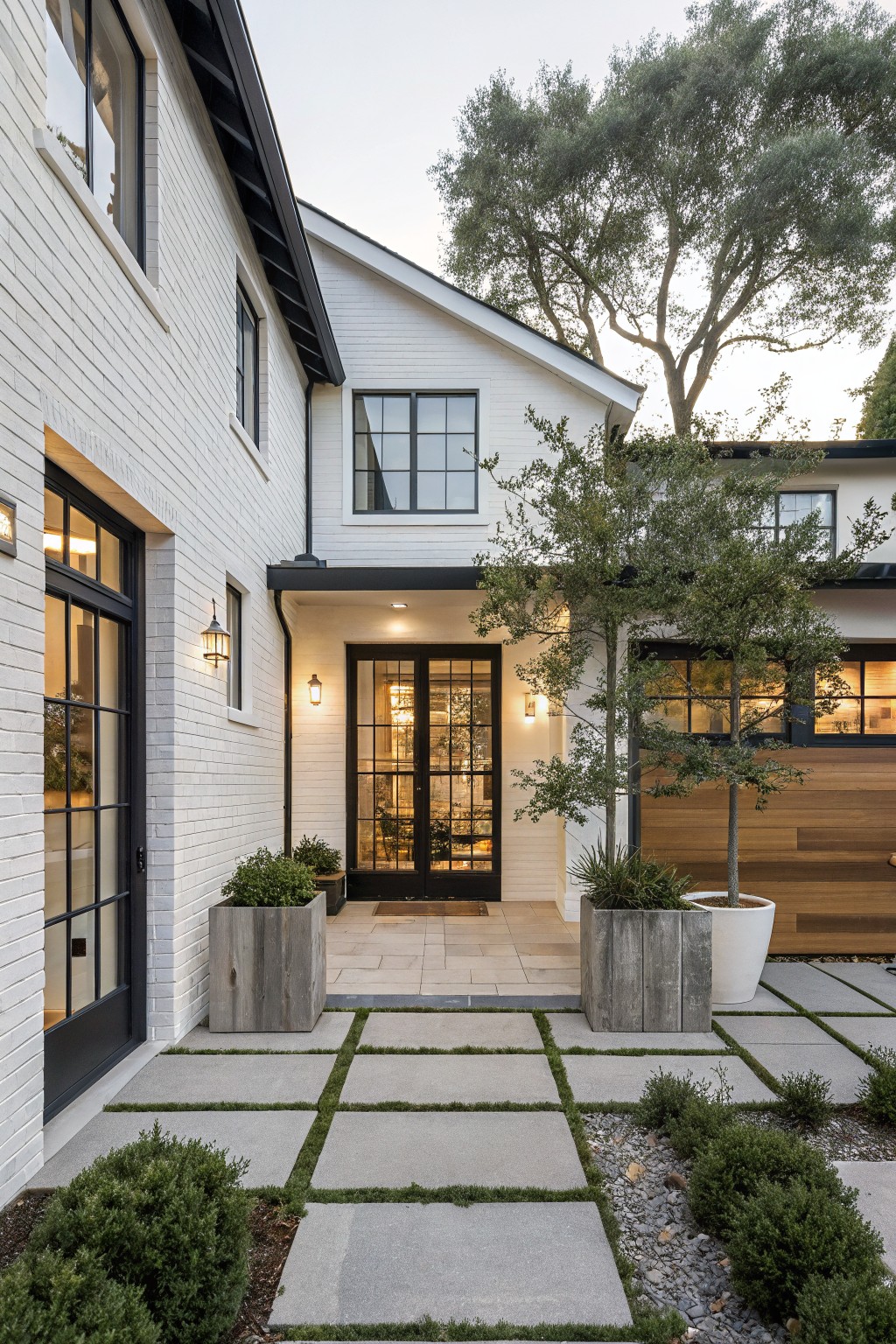 Modern white brick house with black doors, stone path, and landscaped entry.