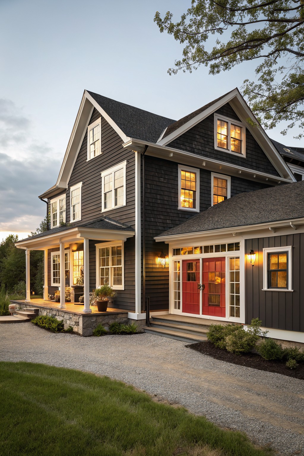 Large dark gray house with red double doors, white trim, and lit windows