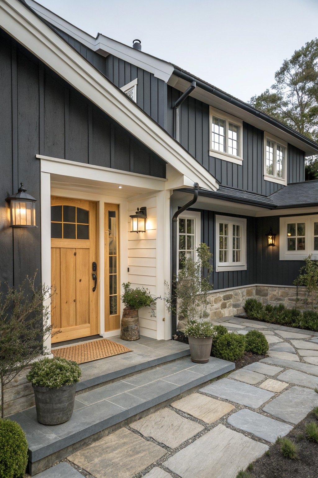 Dark gray house with wooden door, white trim, stone path, and potted plants.