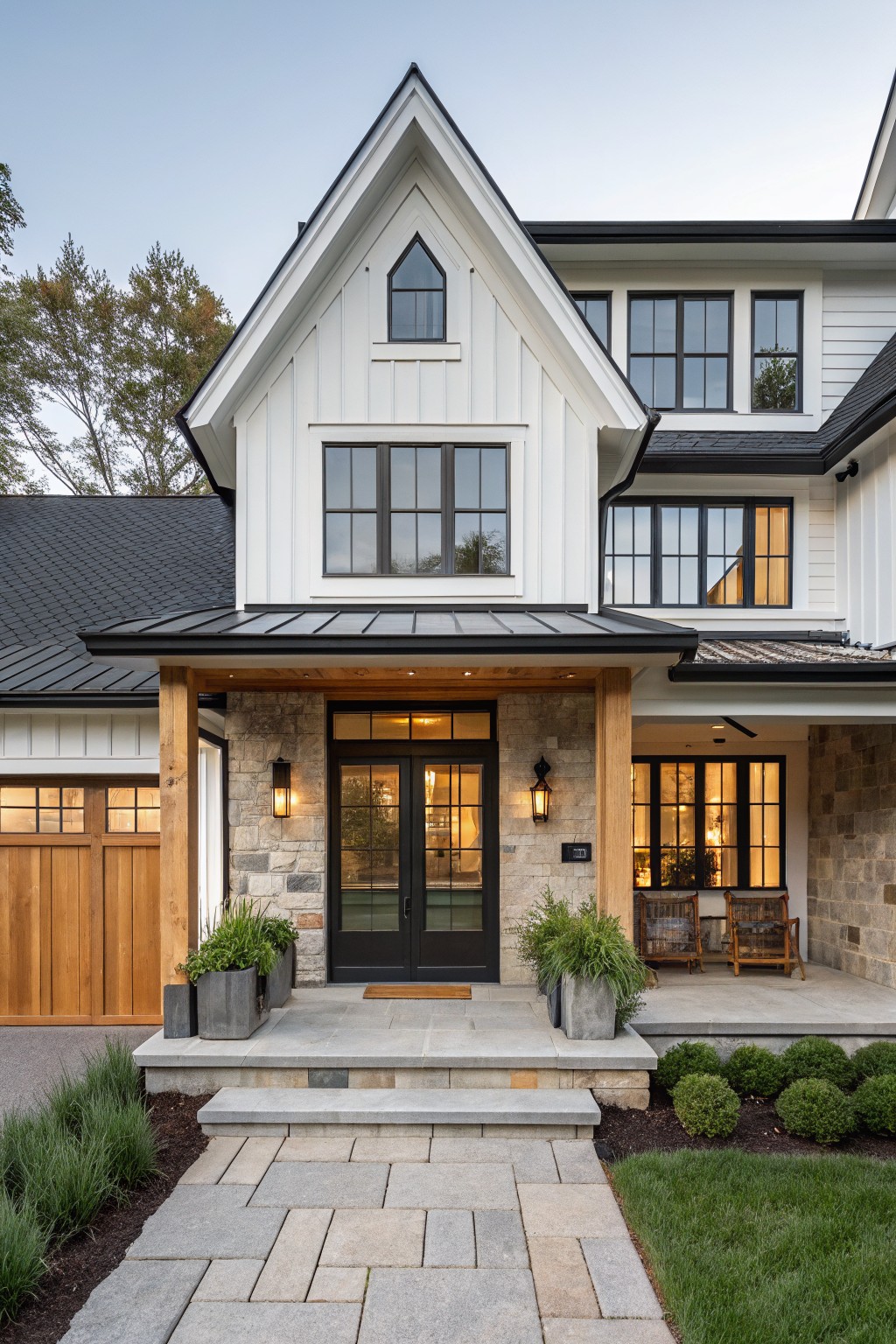 Front view of a white farmhouse with black double doors, stone veneer pillars, wood posts, and a metal roof overhang above the entry.