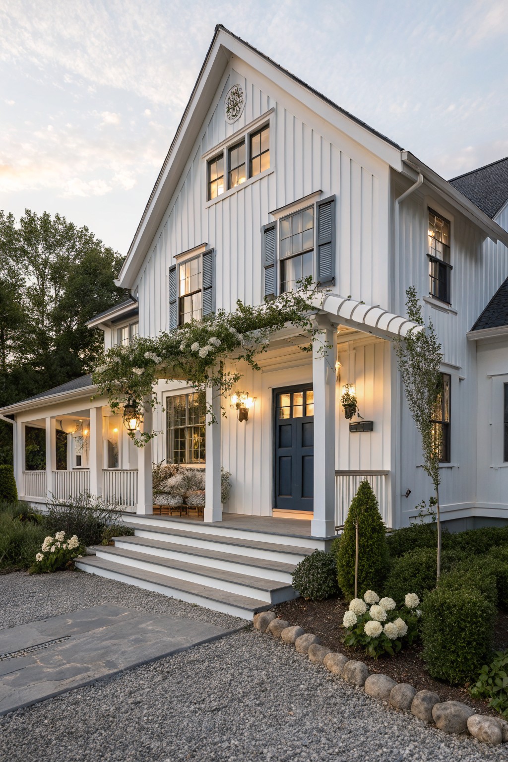 A white two-story farmhouse with a dark blue front door, gray shutters, white trim, and a covered porch.