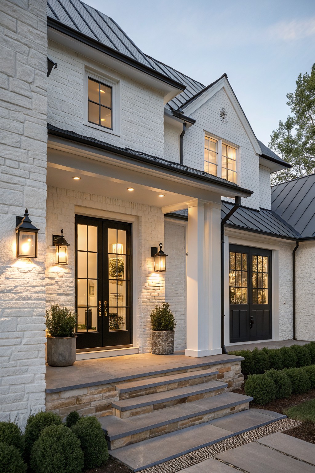 White brick house exterior with dark metal roof, black double doors under a porch, and stone steps leading to the entrance.